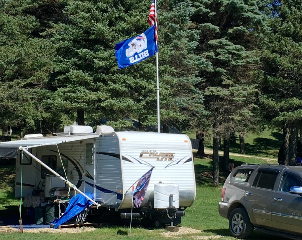 A camping RV parked in a grassy area with a flag at a campground in Western New York.