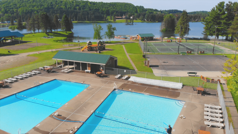 An aerial view of a wny campground with swimming pool and tennis courts.
