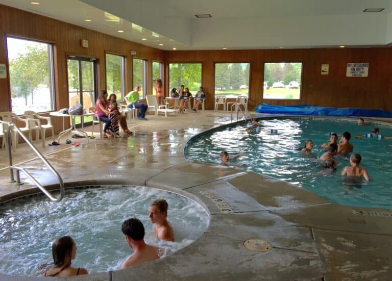 A group of people enjoying the hot tub in a large indoor pool at a cabin in WNY.