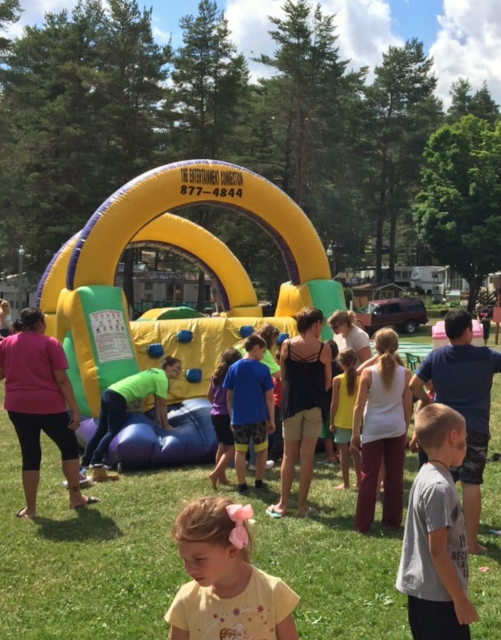 People enjoying an inflatable obstacle course at a Rainbow Lake RV resort.