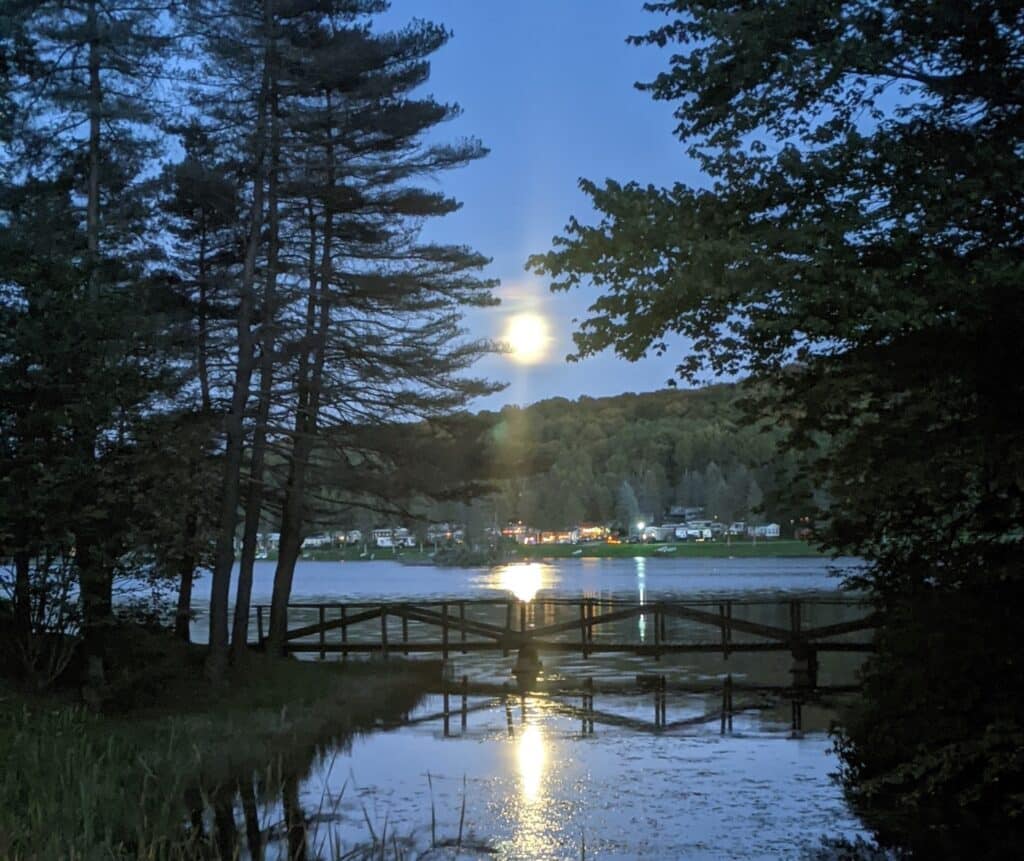 A full moon rises over a campground at night.
