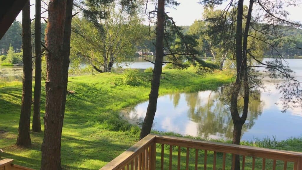 A serene view of Rainbow Lake from a deck in a wooded area, ideal for camping or cabin stays at a campground.