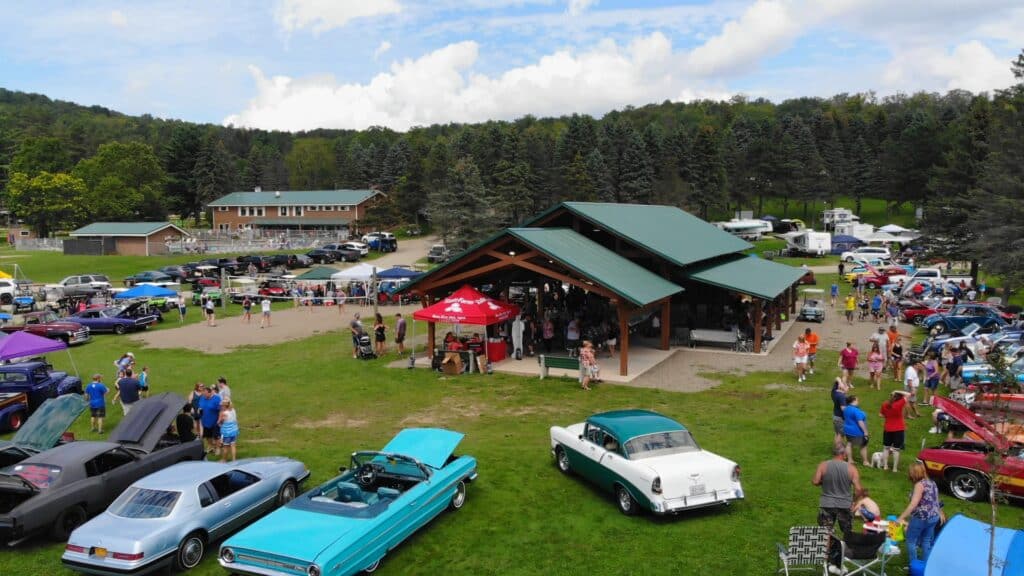 An aerial view of a crowd of people at a car show in a campground.