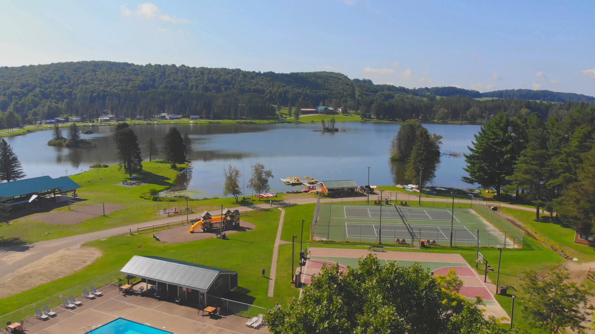 An aerial view of a tennis court situated by a serene lake.