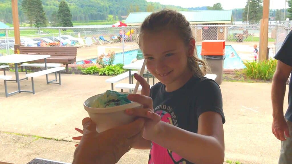 A young girl is holding a cup of ice cream at a cabin in an RV campground.