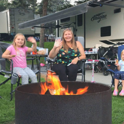 A family sits around a campfire at an RV resort.