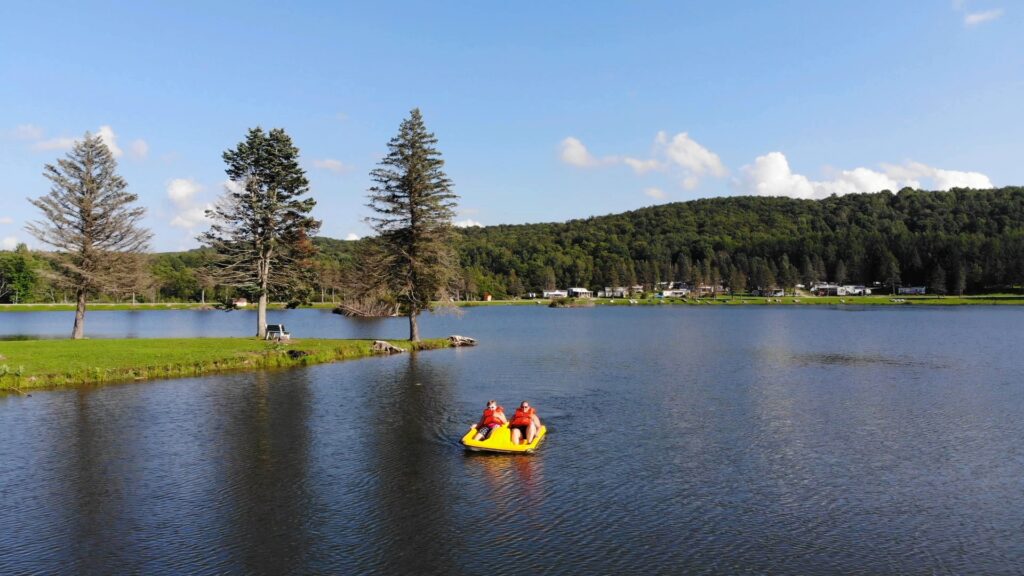 Two people are camping and floating in an inflatable raft on Rainbow Lake in western New York.