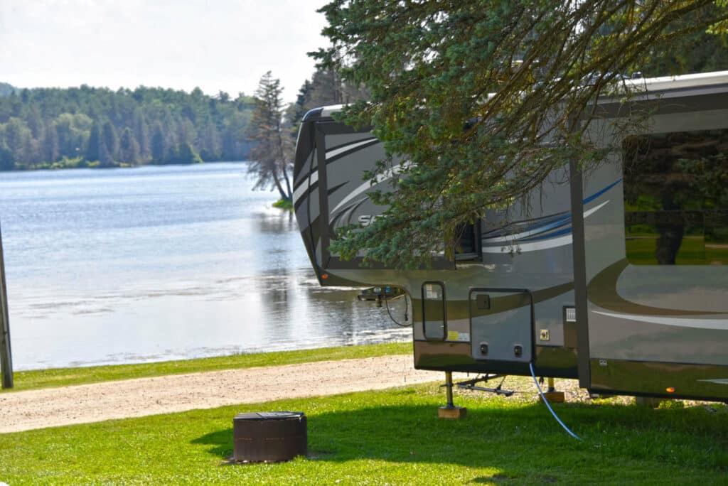 An RV parked next to a Rainbow Lake at a campground.