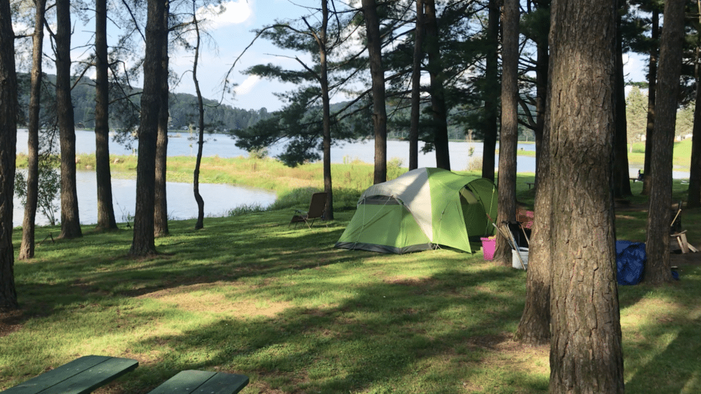 A campground nestled in the woods next to a serene lake.
