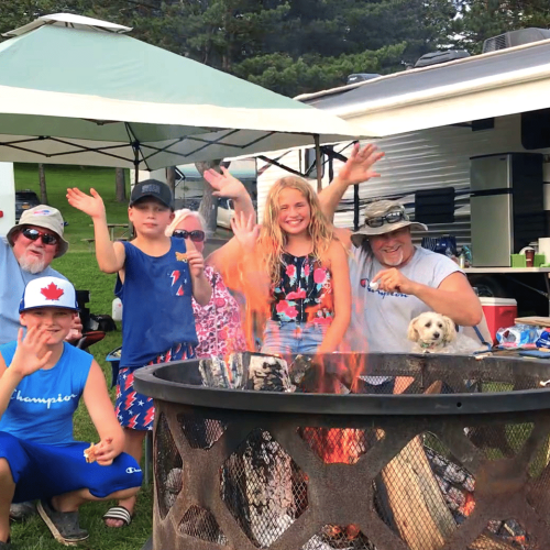 A group of people gathered around a campfire at a campground in Western New York, enjoying the experience of camping.