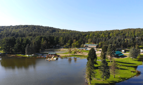 A campground near a lake, surrounded by trees.