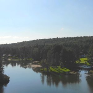 An aerial view of Rainbow Lake surrounded by trees at a family campground.