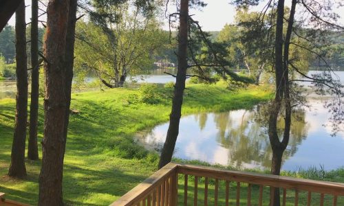 A serene view of Rainbow Lake from a deck in a wooded area, ideal for camping or cabin stays at a campground.