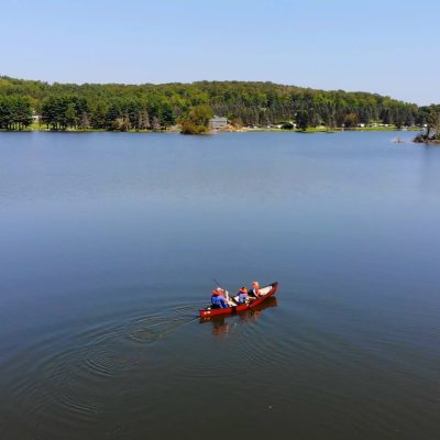 Two people camping in a canoe on Rainbow Lake in Western New York.