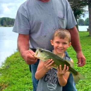 A man and a young boy holding up a large bass at a family campground in Western New York.