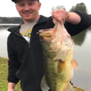 A man holding up a large bass at a family campground.