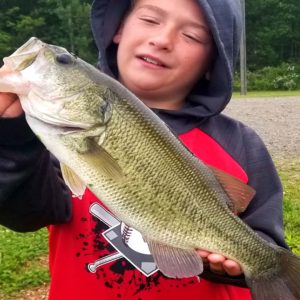 A young boy holding up a large bass at a family campground.