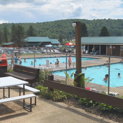 Rainbow Lake, an RV campground with a swimming pool equipped with tables and chairs.