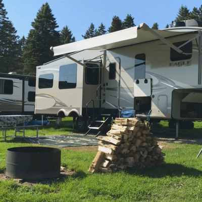 Two RVs parked next to each other in a grassy camping area.