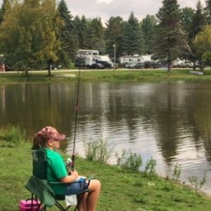 A girl sits in a chair and fishes in Rainbow Lake at a Campground in Western New York.