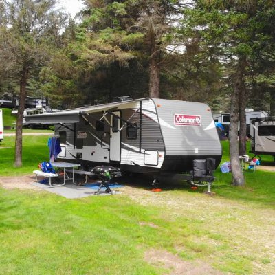 A group of RVs parked in a wooded area at a campground.