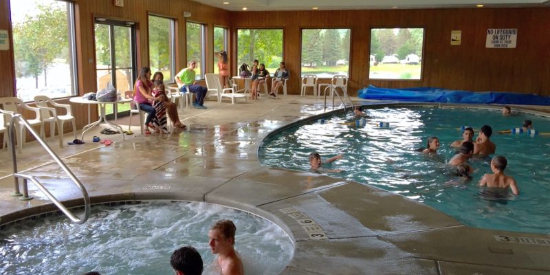A group of people enjoying the hot tub in a large indoor pool at Rainbow Lake campground.