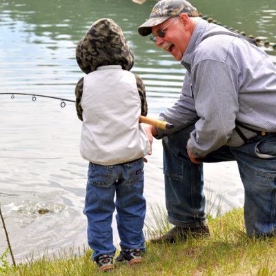 A man is fishing with a little boy at the Rainbow Lake campground.