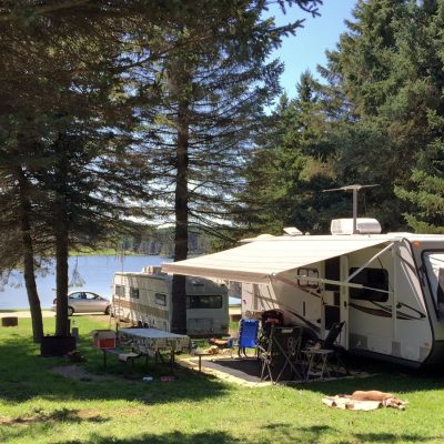 An rv parked in a grassy area near Rainbow Lake.
