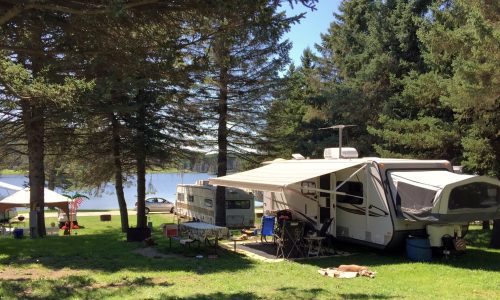 An rv parked in a grassy area near Rainbow Lake.